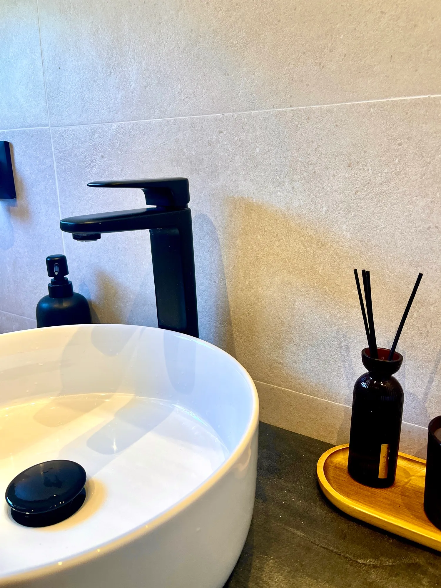 Detalle del lavabo de cerámica con grifería en negro mate y encimera en tono pizarra