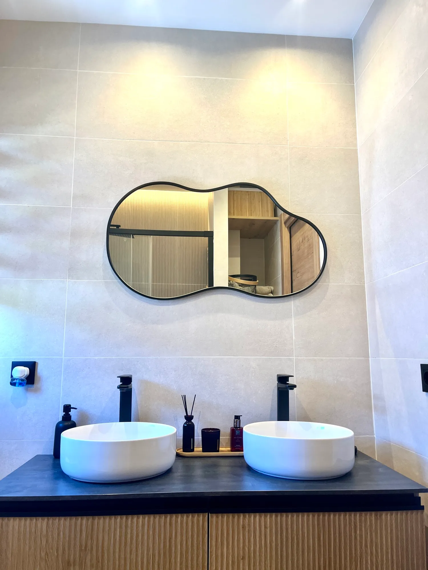 Frente del baño con espejo orgánico, doble lavabo y gres de gran formato