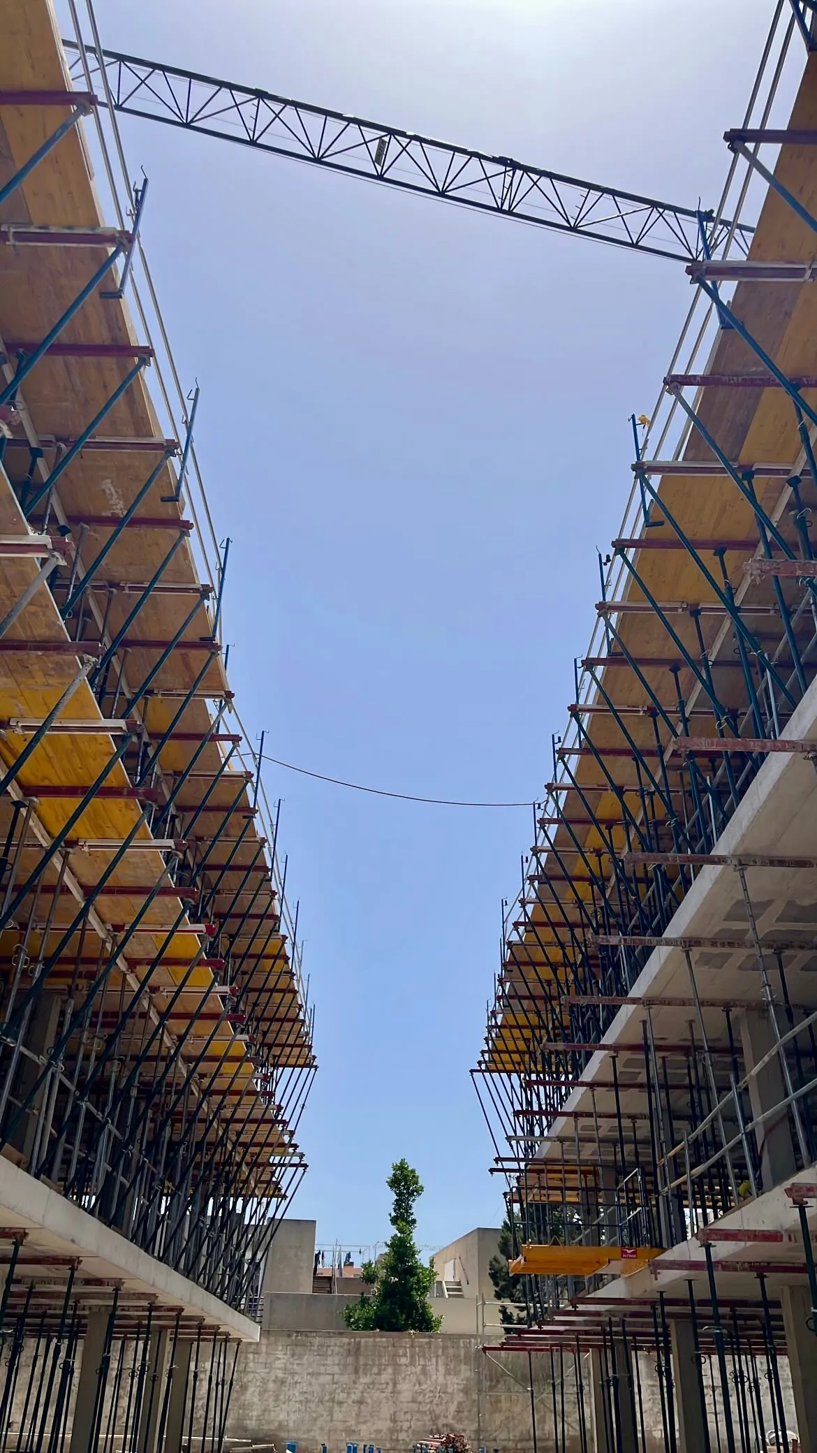 Encofrado y andamios de un edificio en construcción bajo el cielo azul, obra dirigida por Kamay en Ibiza